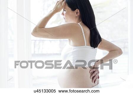 Pregnant woman rubbing back with hand on head View Large Photo Image Stock Photography - Pregnant woman rubbing back with hand on head. Fotosearch