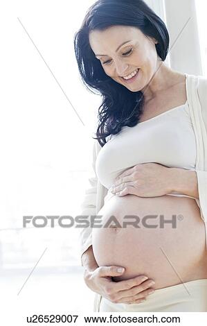 Stock Photo - Pregnant woman touching tummy. Fotosearch
