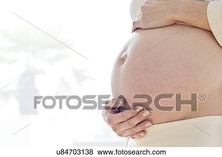 Stock Photo - Pregnant woman touching tummy. Fotosearch