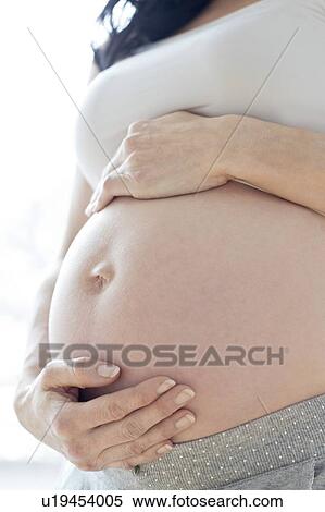 Stock Photography - Pregnant woman touching tummy. Fotosearch