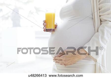 Pregnant woman touching tummy with juice View Large Photo Image Stock Image - Pregnant woman touching tummy with juice. Fotosearch