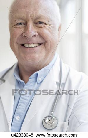 Senior male doctor smiling towards camera View Large Photo Image Stock Photo - Senior male doctor smiling towards camera. Fotosearch