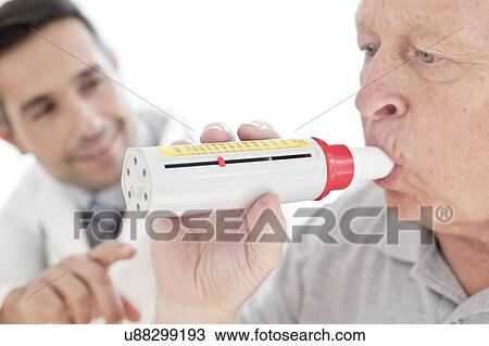 Stock Image - Senior man using peak flow metre. Fotosearch