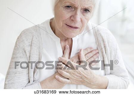 Stock Photo - Senior woman holding chest. Fotosearch
