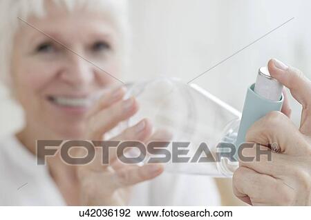 Stock Image - Senior woman holding inhaler. Fotosearch