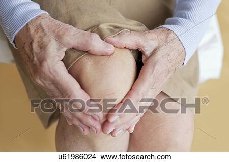 Picture - Senior woman holding sore knee. Fotosearch