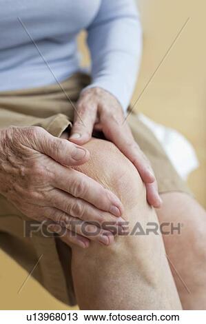 Stock Image - Senior woman holding sore knee. Fotosearch