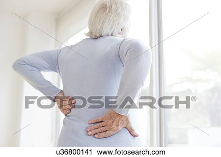 Stock Image - Senior woman rubbing sore back. Fotosearch