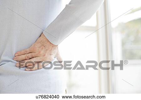 Stock Image - Senior woman rubbing sore back. Fotosearch