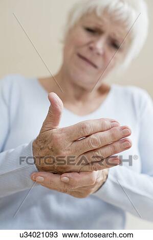 Stock Image - Senior woman touching sore hand. Fotosearch