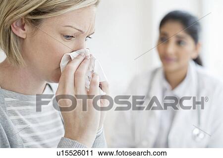 Stock Image - Woman blowing nose. Fotosearch