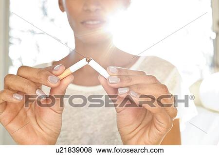 Woman breaking cigarette in half View Large Photo Image Stock Photo - Woman breaking cigarette in half. Fotosearch