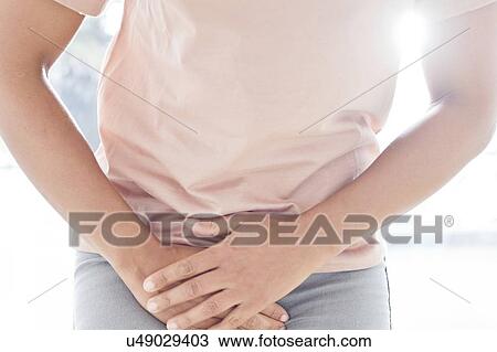 Stock Image - Woman clutching stomach in pain. Fotosearch
