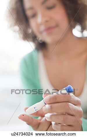 Picture - Woman doing finger prick test. Fotosearch