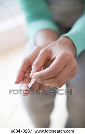 Stock Photo - Woman doing finger prick test. Fotosearch
