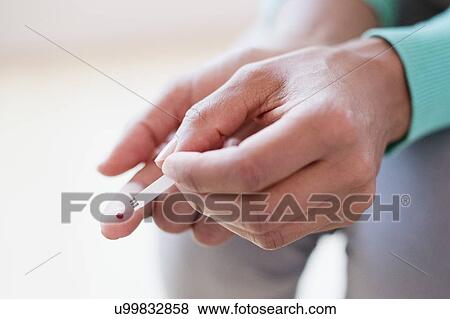 Stock Photo - Woman doing finger prick test. Fotosearch