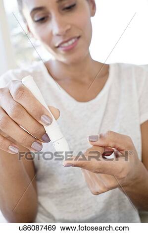 Woman doing pin prick test on finger View Large Photo Image Stock Photo - Woman doing pin prick test on finger. Fotosearch