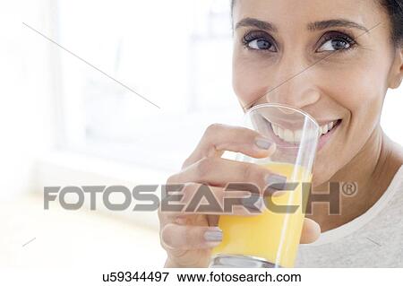 Woman drinking glass of orange juice View Large Photo Image Stock Photo - Woman drinking glass of orange juice. Fotosearch
