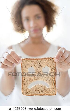 Stock Image - Woman holding bread with sad face. Fotosearch