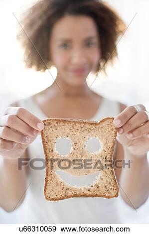 Woman holding bread with smiley face View Large Photo Image Stock Photo - Woman holding bread with smiley face. Fotosearch