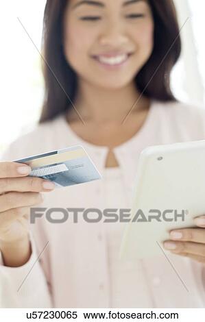 Stock Photography - Woman holding credit card and smartphone. Fotosearch