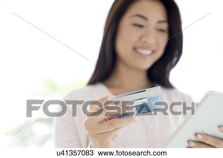 Stock Image - Woman holding credit card and tablet. Fotosearch