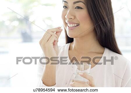 Woman holding pill and glass of water View Large Photo Image Picture - Woman holding pill and glass of water. Fotosearch