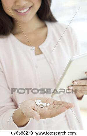 Woman holding pills and digital tablet View Large Photo Image Stock Image - Woman holding pills and digital tablet. Fotosearch