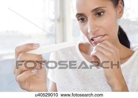Stock Image - Woman holding pregnancy test. Fotosearch