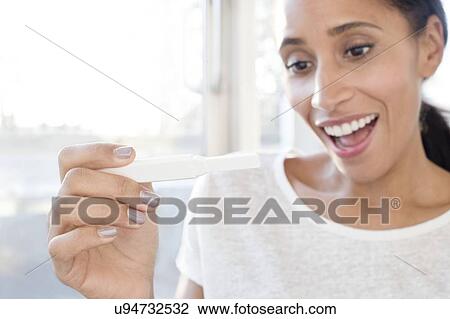 Stock Image - Woman holding pregnancy test. Fotosearch