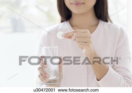 Stock Image - Woman holding tablet and glass of water. Fotosearch