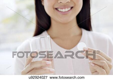 Woman holding tablet and glass of water View Large Photo Image Stock Photo - Woman holding tablet and glass of water. Fotosearch