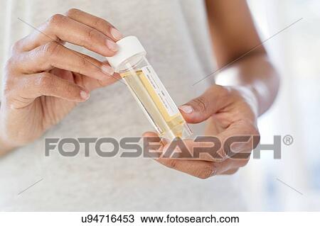 Stock Image - Woman holding urine sample. Fotosearch