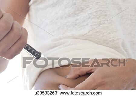 Stock Image - Woman injecting herself in tummy. Fotosearch