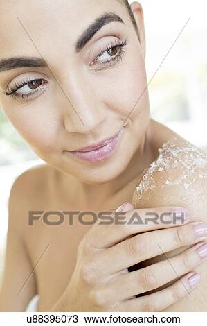 Stock Image - Woman rubbing body scrub on shoulder. Fotosearch