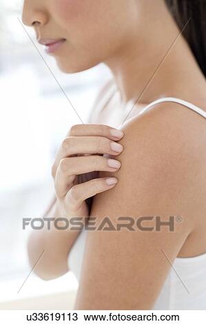 Stock Image - Woman scratching shoulder. Fotosearch