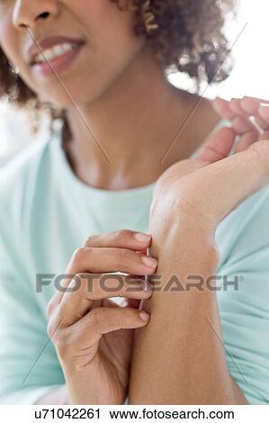 Stock Image - Woman scratching wrist. Fotosearch