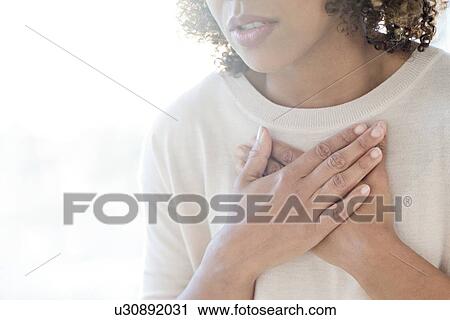 Stock Image - Woman touching her chest. Fotosearch