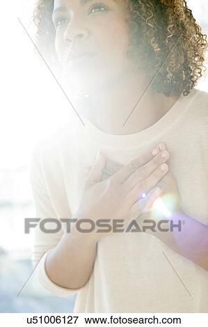 Stock Photo - Woman touching her chest. Fotosearch