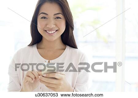 Stock Image - Woman using smartphone, smiling. Fotosearch