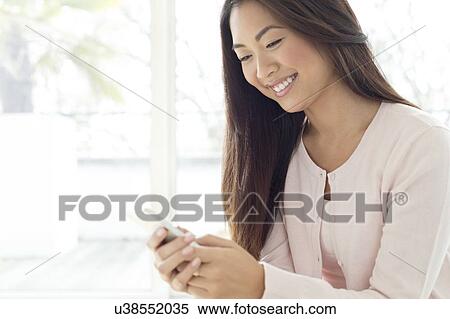 Woman using smartphone, smiling View Large Photo Image Stock Photography - Woman using smartphone, smiling. Fotosearch