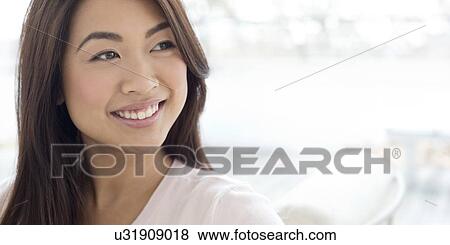 Stock Photo - Woman with brown hair smiling and looking away. Fotosearch