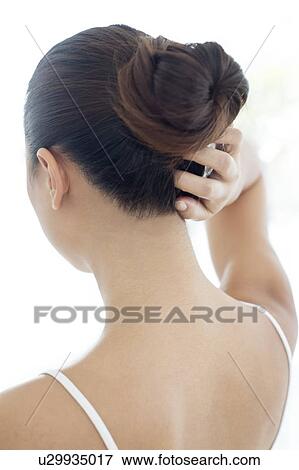 Woman with hair bun scratching head View Large Photo Image Stock Photo - Woman with hair bun scratching head. Fotosearch