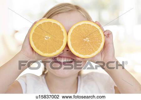 Young girl holding oranges over eyes View Large Photo Image Stock Image - Young girl holding oranges over eyes. Fotosearch