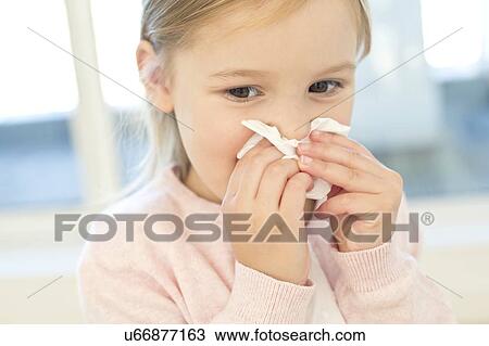 Young girl wiping nose on tissue View Large Photo Image Stock Image - Young girl wiping nose on tissue. Fotosearch