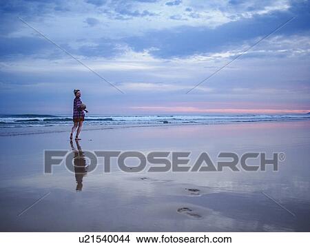 Picture - Australia, New South Wales, Woman standing on beach at dusk. Fotosearch