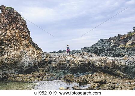 Stock Photo - Australia, New South Wales, Woman standing on cliff and looking at view. Fotosearch
