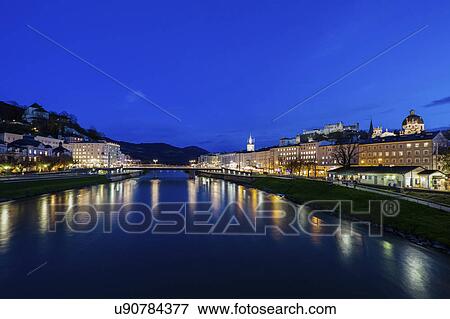 Stock Photo - Austria, Salzburg, Illuminated townhouses in riverbank. Fotosearch