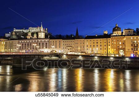 Stock Photo - Austria, Salzburg, Riverbank with buildings at night. Fotosearch