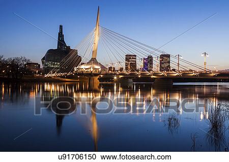Stock Image - Canada, Manitoba, Winnipeg, Red river reflecting Esplanade Riel Bridge. Fotosearch